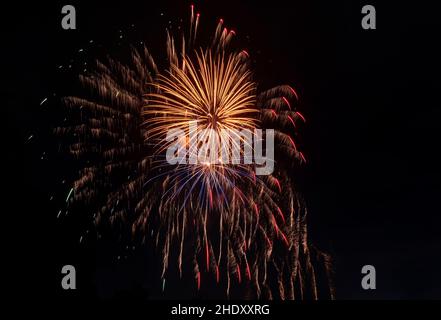 Bright rays of light from explosion of festive fireworks against black background of night sky. Stock Photo