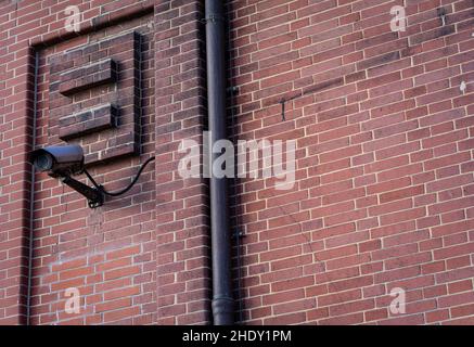 Monitoring Camera mounted on an outer wall made of red bricks. Stock Photo