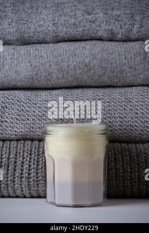 homemade scented multicoloured beige candle in mason jar with gray knit sweaters in a wooden box. Handmade craft organic gift. Monochrome product adve Stock Photo