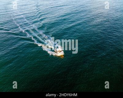 High angle drone view of fast boat floating on rippling sea and splashing clean water in daytime Stock Photo