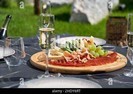 Snack for guests. A plate of cheese, salami, nuts, grapes and snacks on a tray. Antipasto. Italian food. Stock Photo