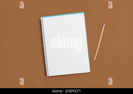 A blank notebook and a pencil on a brown background Stock Photo