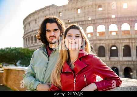 Young couple traveling to Rome. The couple is posing for a photo in front of the Colosseum. Stock Photo