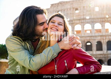 Young couple traveling to Rome. The couple is kissing in front of the Colosseum. Stock Photo