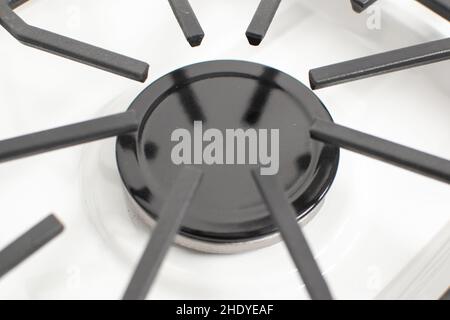 Close-up shot of a gas burner on a white enamelled hob with cast iron pan supports Stock Photo