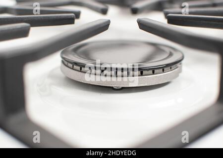 Close-up shot of a gas burner on a white enamelled hob with cast iron pan supports Stock Photo