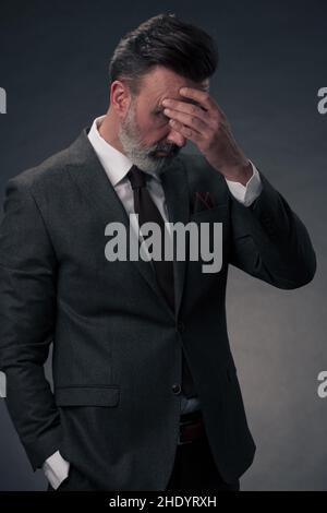 Frustrated middle aged elegant man Close up face of stressed businessman wearing stylish suit with eyes closed. Overworked middle eastern business man Stock Photo