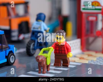 Tambov, Russian Federation - January 07, 2022 A Lego blind or partially-sighted person minifigure with a guide dog crossing the road using a pedestria Stock Photo