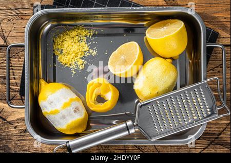 Cooking with Grated Lemon Zest and spiral peel in kitchen tray. Wooden background. Top view Stock Photo