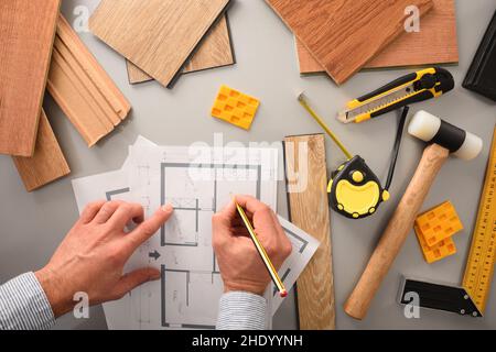 Hands on designer on desk writing on blueprints developing interior project with wood samples and tools. Top view. Stock Photo