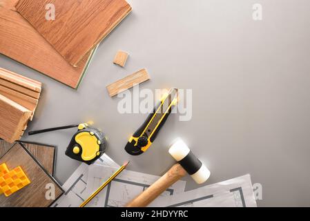 Detail of materials and tools on the work table of a parquet installer with plans. Top view. Stock Photo