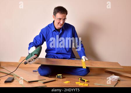 Professional parquet assembler with cutting machine ready to cut slat for mounting parquet in the home. Horizontal composition. Stock Photo