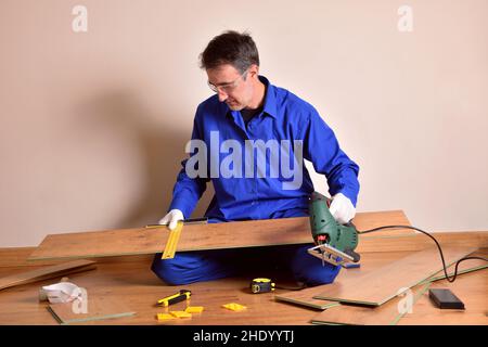 Parquet assembler worker with cutting machine ready to cut plank for parquet assembly in home. Horizontal composition. Stock Photo