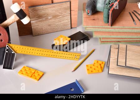 laminated flooring and assorted tools for placement on a gray table. Elevated view. Horizontal composition. Stock Photo