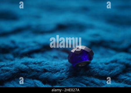 Dark blue crystal on a blue knitted table. Stock Photo