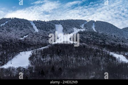 Ski lift transporting skiers to the top of a snow covered mountain. Stock Photo