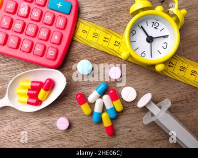 Spoon,syringe,calculator,measuring tape,clock and pills capsules on a wooden background.Selective focus. Healthcare and medical concept. Stock Photo
