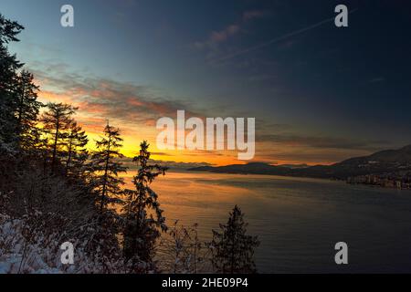View from the winter, snow-covered forest at sunrise over the mountains and the sea near the modern city Stock Photo