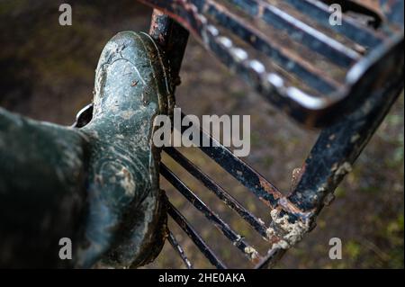 A foot in a muddy wellington on the step to the tractor. Stock Photo