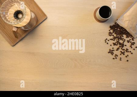 Overhead view of coffee beans with cup and filtration containers on table Stock Photo