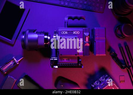 Overhead view of cinema camera and computer parts on colorful illuminated table Stock Photo