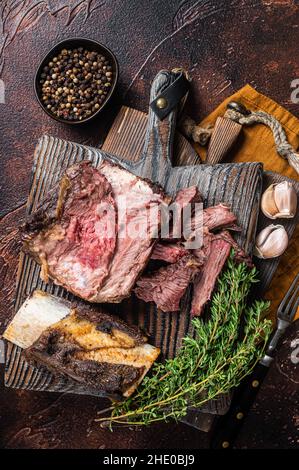 Braised veal beef short ribs on wooden cutting board with thyme. Dark background. Top view Stock Photo