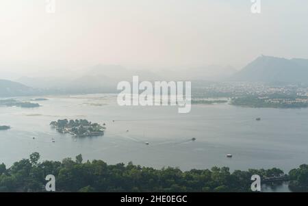 Elevated view of lake Pichola flanked by Aravallli hills at sunrise on a misty morning  in summer in Udaipur, Rajasthan, India. Stock Photo