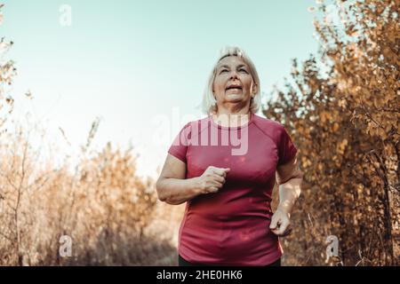 Beautiful sporty mature female runs staying fit with sport. Sport, cardio, workout concept Stock Photo