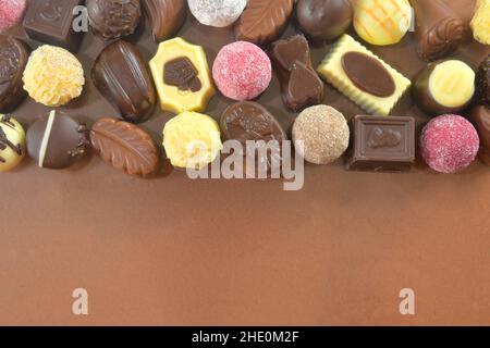 Chocolate cookies and pralines for a holiday event on a brown background with large copy space. Flat lay Stock Photo