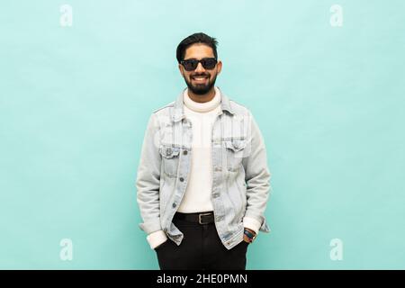 Photo of confident cheerful handsome indian man summer vacation wear sunglass green hoodie isolated teal color background Stock Photo