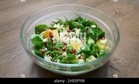 Fresh green salad with chicken, garnet and orange on wooden background top view. Healthy food Stock Photo