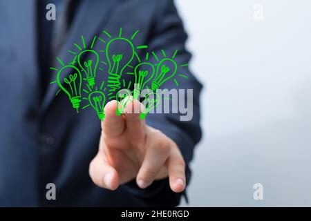 Male pointing to an illustration of green light bulbs - eco-friendly business Stock Photo