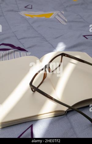 open notebook, detail in its blank sheets, on top of glasses for reading, lifestyle and intellectual pastimes, background Stock Photo