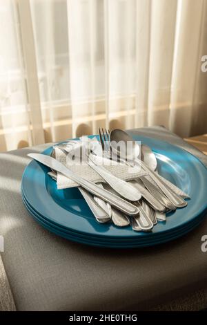 colorful plate stacked with cutlery and napkins, details of metal utensils, domestic life objects in studio, kitchen Stock Photo