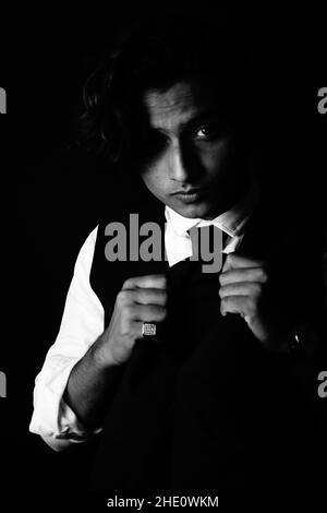 Vertical shot of an attractive Indian gentleman posing in classic clothes and wearing a finger ring Stock Photo