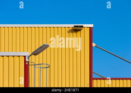 View of a yellow container of Hazardous Material goods with a lamp against a light sky Stock Photo
