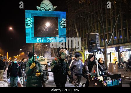 Protesters carry a placard depicting a TV screen with initials of the leading government party Slovenian Democratic Party(SDS), being held by a caricature of the Prime Minister Janez Jansa as they march the streets during an anti-government protest.For the 90th consecutive Friday, people in Ljubljana have protested against the government of Prime Minister Janez Jansa and its alleged dismantling of democracy in the country. The latest protest addressed the national television's management refusing to renew contracts to an entire ensemble of columnists for a critical TV programme Studio City, wh Stock Photo