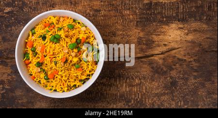 cup of crispy and spicy masala mix chips, made with flour, green peas, fried lentils, nuts and rice puffs, quick snack on a wooden surface, copy space Stock Photo