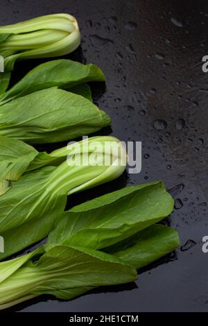 Freshly washed raw Bok choy on black table with water droplets Stock Photo