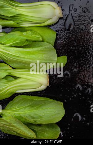 Freshly washed raw Bok choy on black table with water droplets Stock Photo