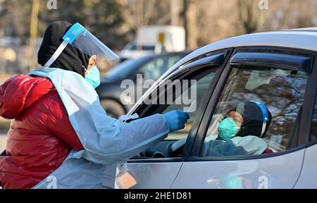 Wilkes-Barre, Pennsylvania, USA. 6th Jan, 2022. A healthcare worker wearing a Personal Protective Equipment (PPE) gear collects a swab sample from a person at a drive thru testing site.With the new Omicron variant Covid-19 surge, testing sites are seeing long lines for testing. Employees from AMI Expeditionary Healthcare are seen in Pennsylvania giving Covid-19 tests. The group has been moving from hotel to hotel and working 12 hour days, 4-5 days a week to test community members for Covid-19. (Credit Image: © Aimee Dilger/SOPA Images via ZUMA Press Wire) Stock Photo