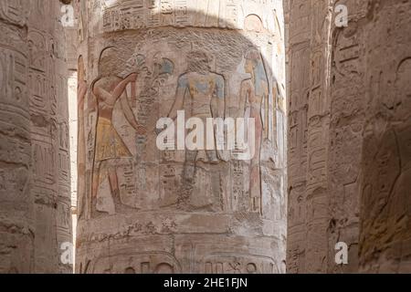 Figures in the Hypostyle hall at Karnak temple, the relief sculptures are well preserved even retaining paint although the faces were chipped off. Stock Photo