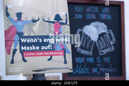 Bielefeld, Germany. 08th Jan, 2022. 'When the going gets tough: Mask on!' is written on a sign in the pedestrian zone in front of a pub. Credit: Friso Gentsch/dpa/Alamy Live News Stock Photo