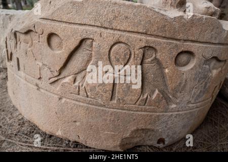 The broken base of a statue with 2 falcons and an ankh as well as other hieroglyphs inscribed on it in Memphis, Egypt. Stock Photo