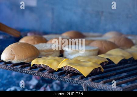 Closeup of burger buns, meat and melted cheese on top getting prepared for serving Stock Photo