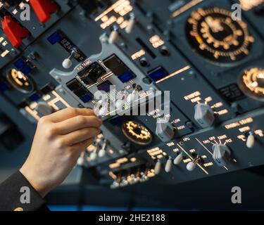 Close-up of a pilot's hand turning a toggle switch on the control panel. Stock Photo