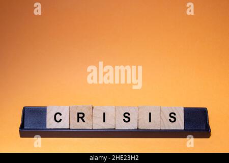 CRISIS. Word written on square wooden tiles with an orange background. Horizontal photography. Stock Photo