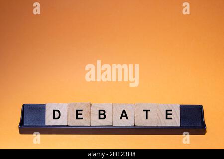 DEBATE. Word written on square wooden tiles with an orange background. Horizontal photography. Stock Photo