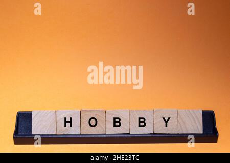 HOBBY. Word written on square wooden tiles with an orange background. Horizontal photography. Stock Photo