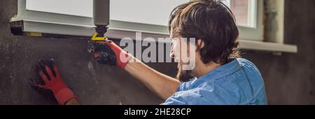 Man in a blue shirt does window installation BANNER, LONG FORMAT Stock Photo